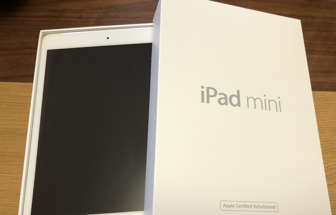 机の上に置かれたiPad miniの箱と本体。箱の下部に「Apple Certified Refurbished」と書かれている